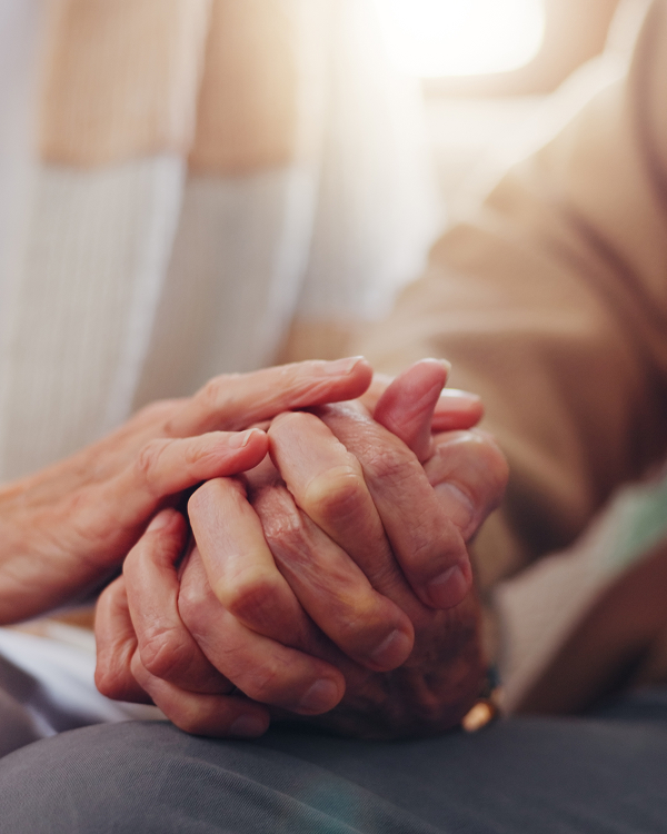 Close-up of two elderly people holding hands, showing gentle support and connection.